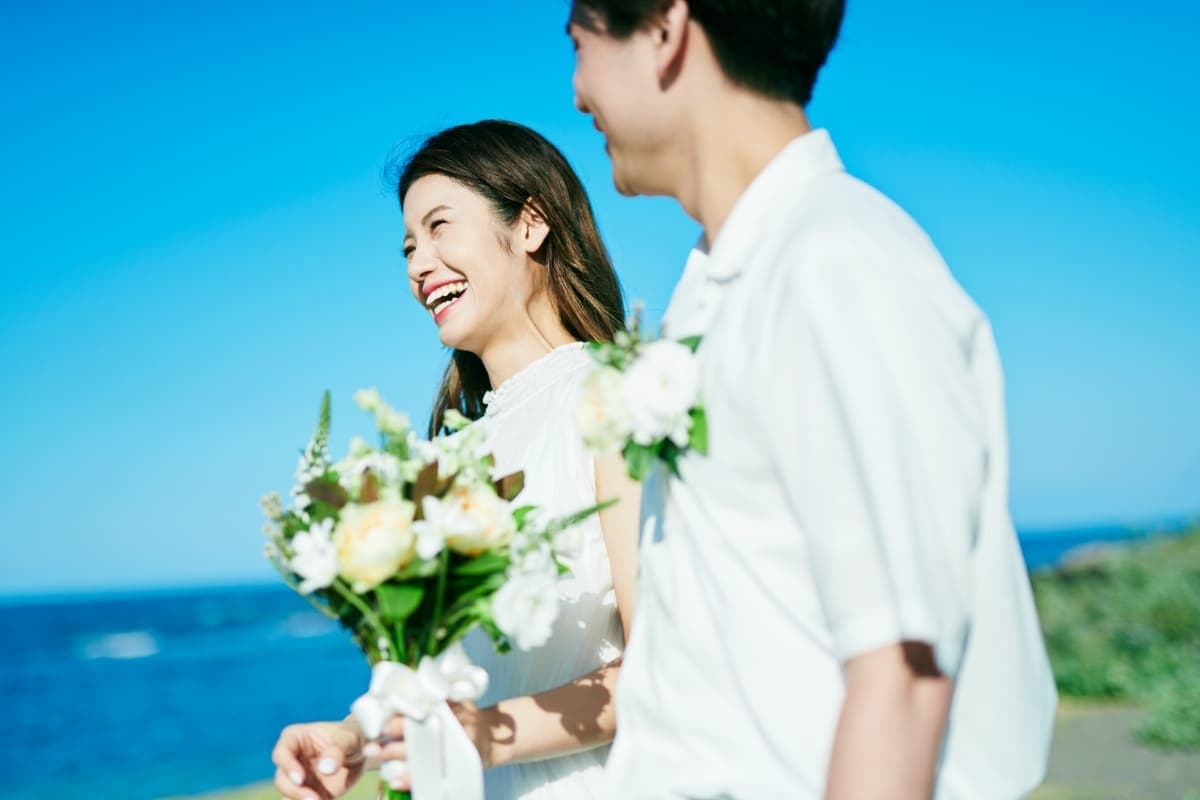 青空の下、海辺で微笑むカップル。